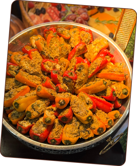 A large silver bowl brimming with small, colorful bell peppers, stuffed with a savory filling.
